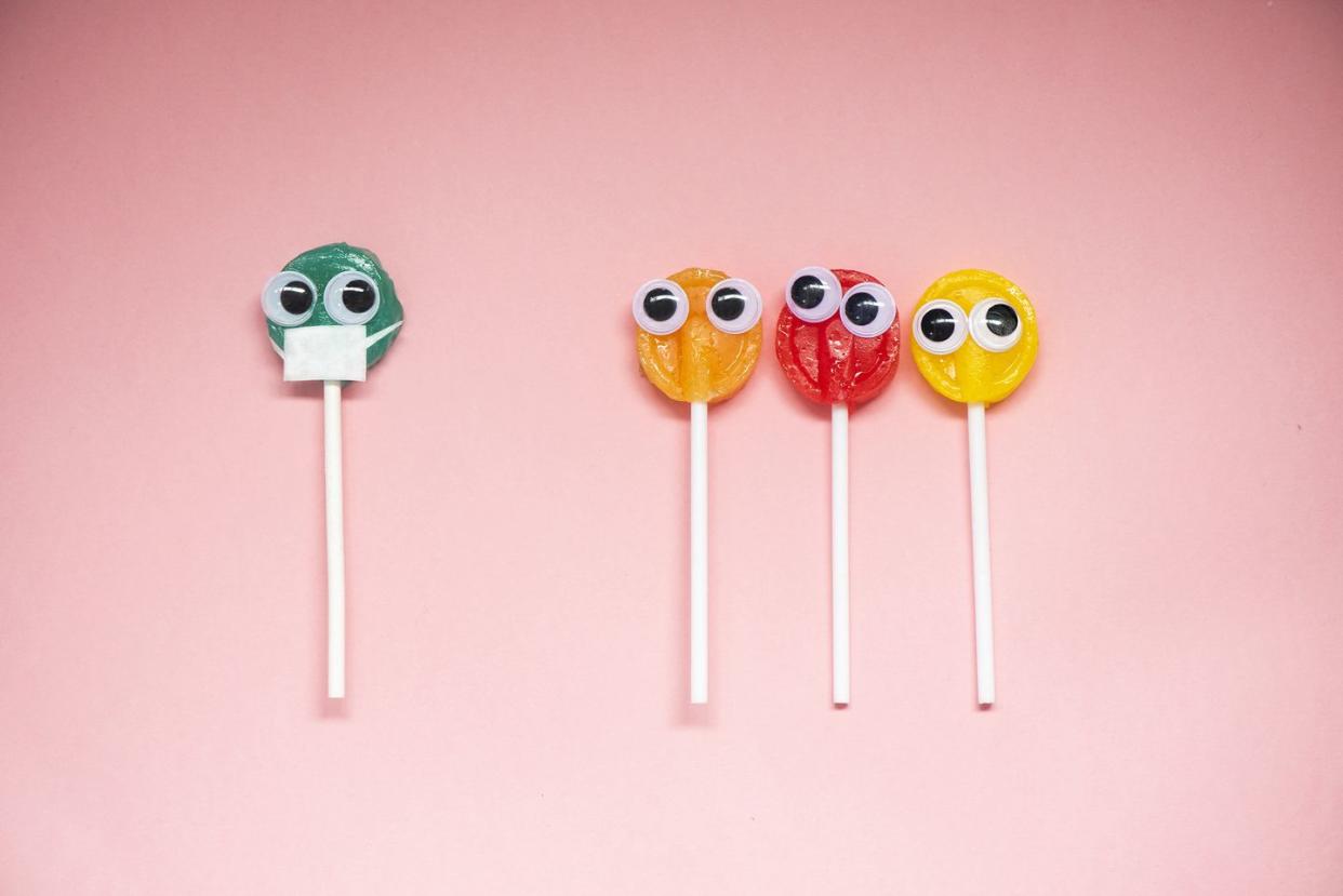 lollipop with cartoon eyes on pink colored background, social distancing concept