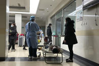 A hospital worker prepares to perform tests after placing electrodes to the chest of a man sprawled out on a stretcher outside the emergency ward at the Langfang No. 4 People's Hospital in Bazhou city in northern China's Hebei province on Thursday, Dec. 22, 2022. As China grapples with its first-ever wave of COVID mass infections, emergency wards in the towns and cities to Beijing's southwest are overwhelmed. Intensive care units are turning away ambulances, residents are driving sick relatives from hospital to hospital, and patients are lying on floors for a lack of space. (AP Photo)