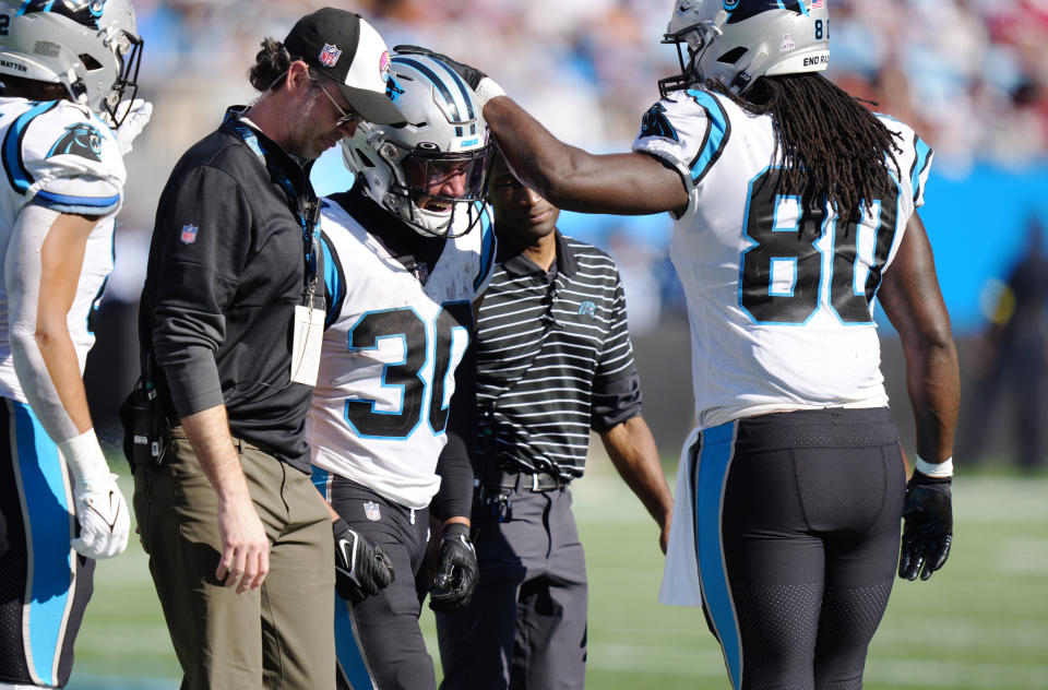 Carolina Panthers running back Chuba Hubbard (30) is helped to the sidelines after being shaken up on a play as teammate tight end Ian Thomas (80) consoles him during the second half of an NFL football game against the Tampa Bay Buccaneers Sunday, Oct. 23, 2022, in Charlotte, N.C. (AP Photo/Jacob Kupferman)