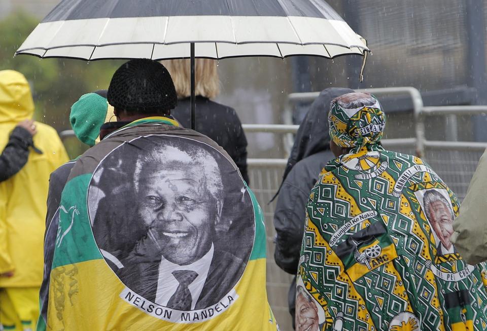 People draped in flags bearing the image of Nelson Mandela arrive for the memorial service for former South African president Nelson Mandela at the FNB Stadium in Soweto, near Johannesburg, South Africa, Tuesday Dec. 10, 2013. (AP Photo/Tsvangirayi Mukwazhi)