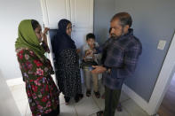 Abdul, right, who worked as a mechanic before he left Kabul, Afghanistan with his family about a month ago, shows his family a donated tea kettle as they stand in the kitchen of a rental house, Thursday, Sept. 16, 2021, that has been provided as a place for them to stay in Seattle. The home is owned by Thuy Do, who was nine years old when her family arrived in the United States from Vietnam in the 1980s. Now Do and her husband have offered their vacant rental home to refugee resettlement groups to house newly arriving Afghans in need of a place to stay. (AP Photo/Ted S. Warren)