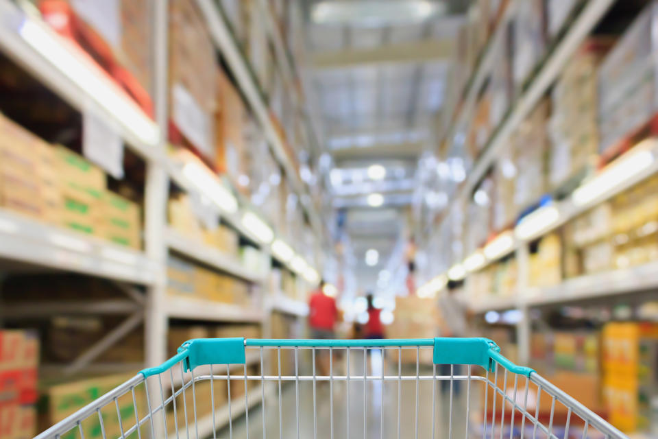 A shopping cart in the aisle of a wholesale store.