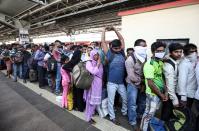 Migrant workers and their families queue to board a train at a railway station, after government imposed restrictions on public gatherings in attempts to prevent spread of coronavirus disease (COVID-19), in Mumbai, India, March 21, 2020. REUTERS/Prashant Waydande