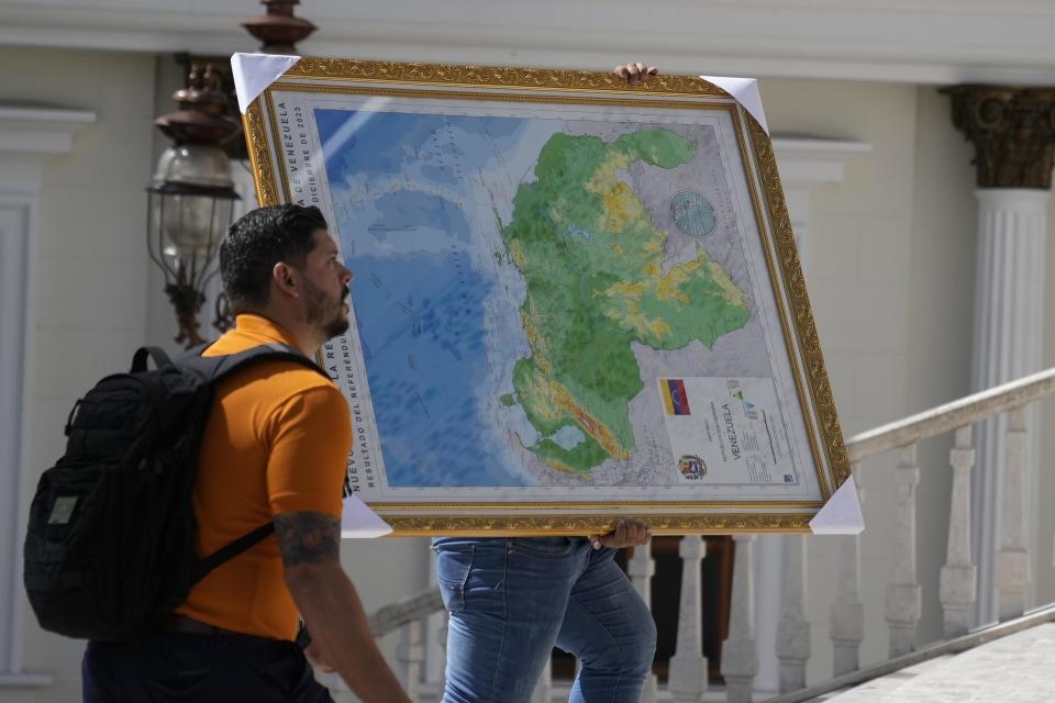 A man carries the new map of Venezuela with the Essequibo territory, a large swath of land that is administered and controlled by Guyana but claimed by Venezuela, to the National Assembly building in Caracas, Venezuela, Wednesday, Dec. 6, 2023. / Credit: Ariana Cubillos / AP