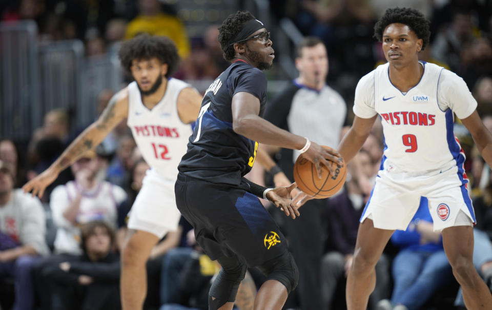 Denver Nuggets guard Reggie Jackson, center, looks to pass the ball as Detroit Pistons forwards Isaiah Livers, left, and Ausar Thompson, right, defend in the second half of an NBA basketball game Sunday, Jan. 7, 2024, in Denver. (AP Photo/David Zalubowski)