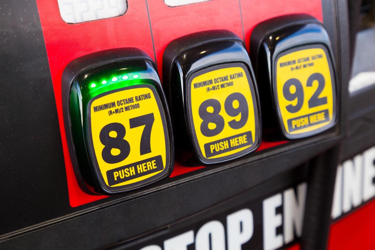 Closeup of three yellow buttons for gas options '87', '89', and '92' at a gas pump with rest of surrounding gas pump area blurred