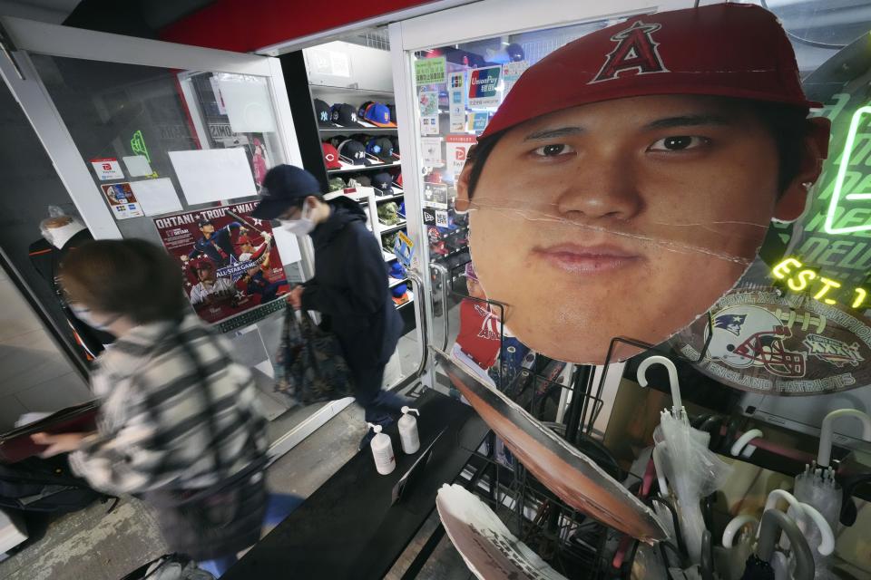 Customers walk out of a sporting goods store after buying some character goods of Shohei Ohtani of the Los Angeles Dodgers in Shinjuku district Wednesday, Dec. 13, 2023, in Tokyo. Ohtani agreed to a record $700 million, 10-year contract with the Los Angeles Dodgers. (AP Photo/Eugene Hoshiko)