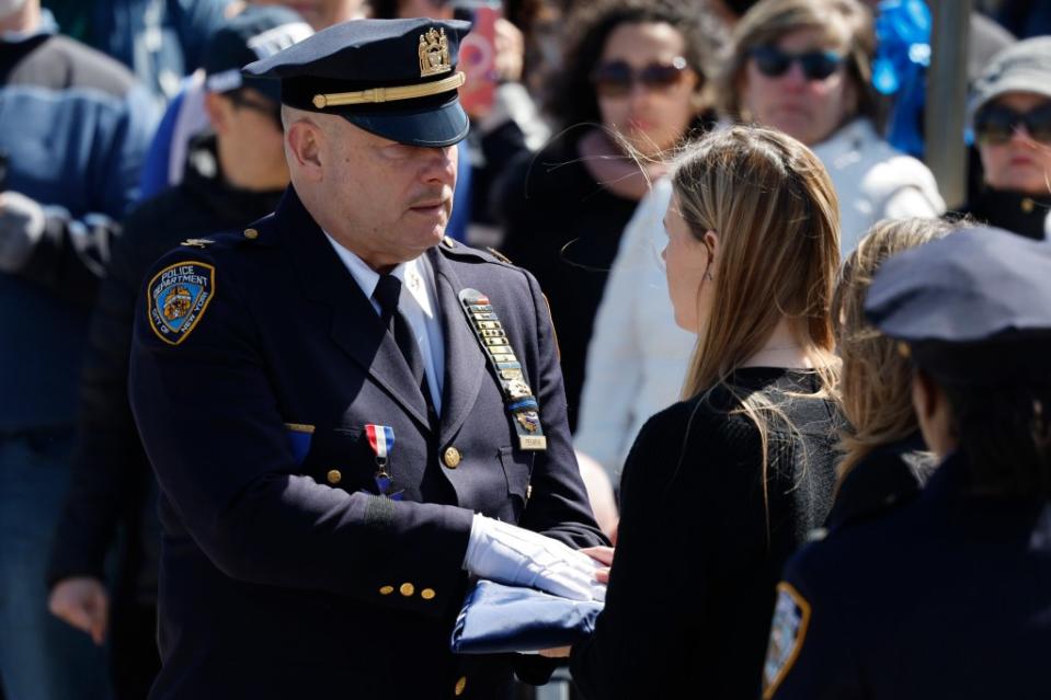 An NYPD officer hands a folded flag to Stephanie Diller, the widow of NYPD officer Jonathan Diller, at his funeral. Getty Images