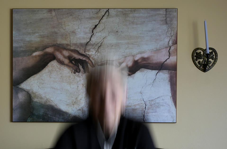 Deb Robertson poses for a portrait in the living room of her Lombard, Ill. home, in front of a reproduction of "The Creation of Adam" fresco painting by Michelangelo, Thursday, March 21, 2024. Robertson didn't cry when she learned two months ago that the cancerous tumors in her liver were spreading, portending a tormented death. But later, she cried after receiving a call that a bill moving through the Illinois Legislature to allow certain terminally ill patients to end their own lives with a doctor's help had made progress. (AP Photo/Charles Rex Arbogast)