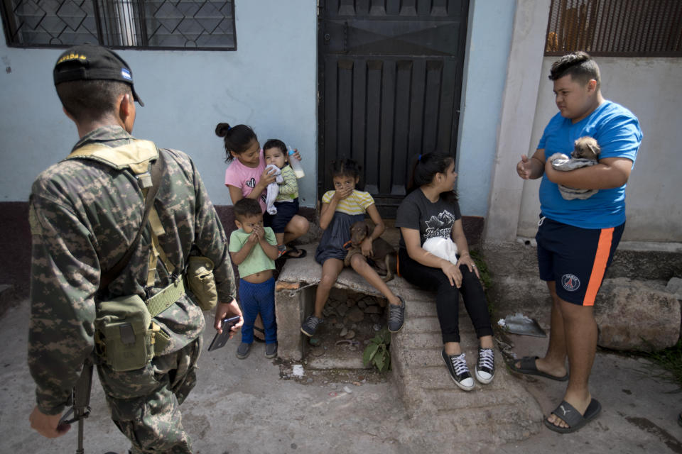 In this photo taken on Aug. 22, 2019, a Honduran soldier watches children while a house is being sprayed in an attempt to control the spread of mosquito-borne diseases in Tegucigalpa, Honduras. At least 135 people have died from dengue this year in Honduras, nearly two-thirds of them children. (AP Photo/Eduardo Verdugo)