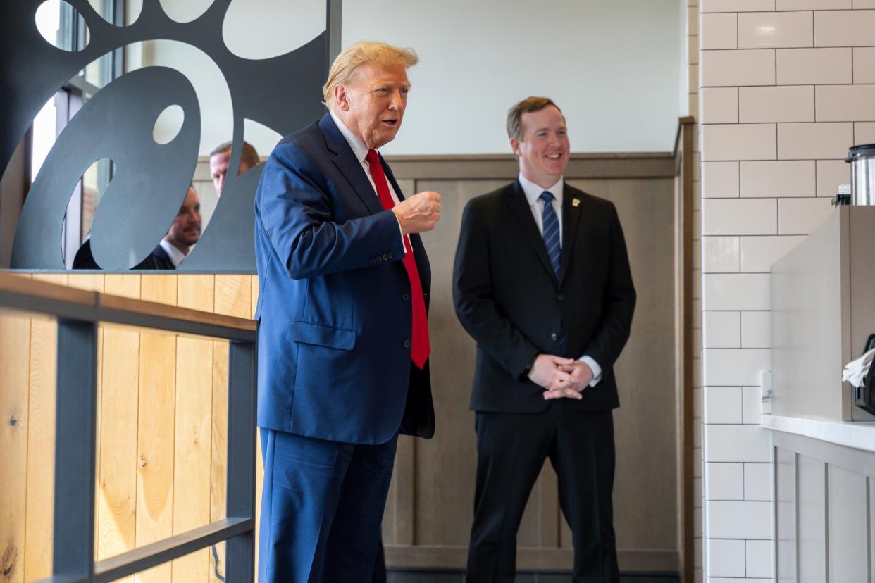 Republican presidential candidate former President Donald Trump, left, visits a Chick-fil-A eatery on 10 April 2024 (AP)