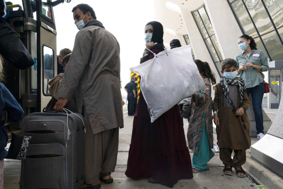 Children accompanied by their families evacuated from Kabul, Afghanistan, board a bus after they arrived at Washington Dulles International Airport, in Chantilly, Va., on Friday, Aug. 27, 2021. (AP Photo/Jose Luis Magana)