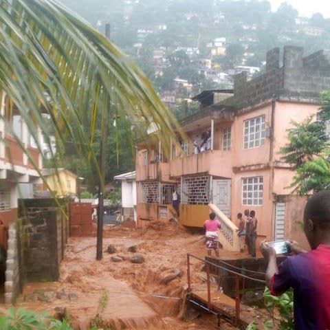 Villagers look on in this image that reportedly shows the aftermath of the Sierra Leone mudslide - Credit: Society for Climate Change Communication Sierra Leone