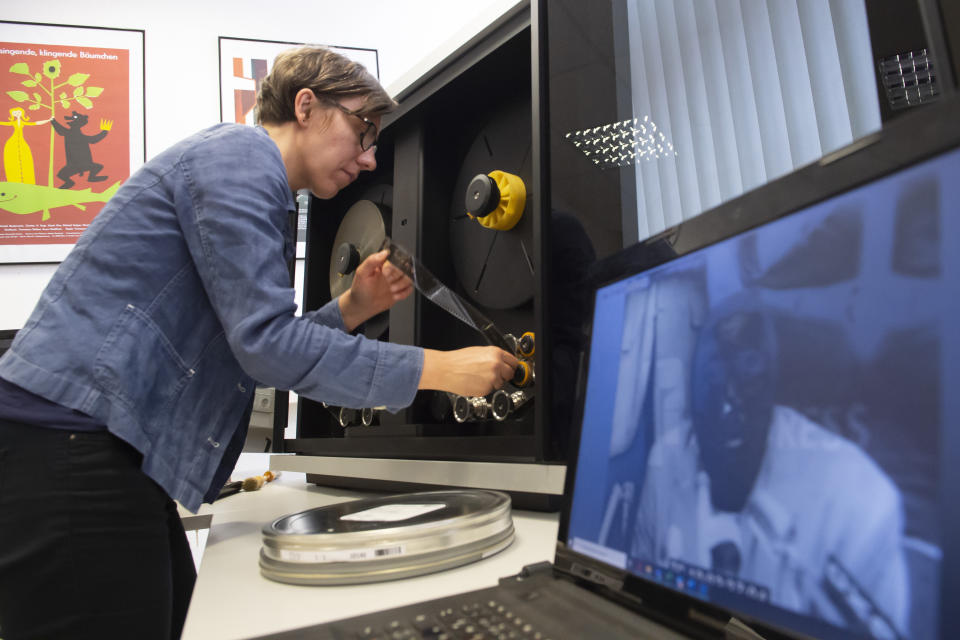 In this Wednesday, June 17, 2020 photo, archive employee Nora Freytag fixes a film roll for digitalization at PROGRESS Film, in Leipzig, Germany. A new project is underway to digitize thousands of East German newsreels, documentaries and feature films 30 years after Germany’s reunification. The movies that are being scanned, transcribed and posted online provide a look inside a country that no longer exists but was a critical part of the Cold War. (AP Photo/Jens Meyer)