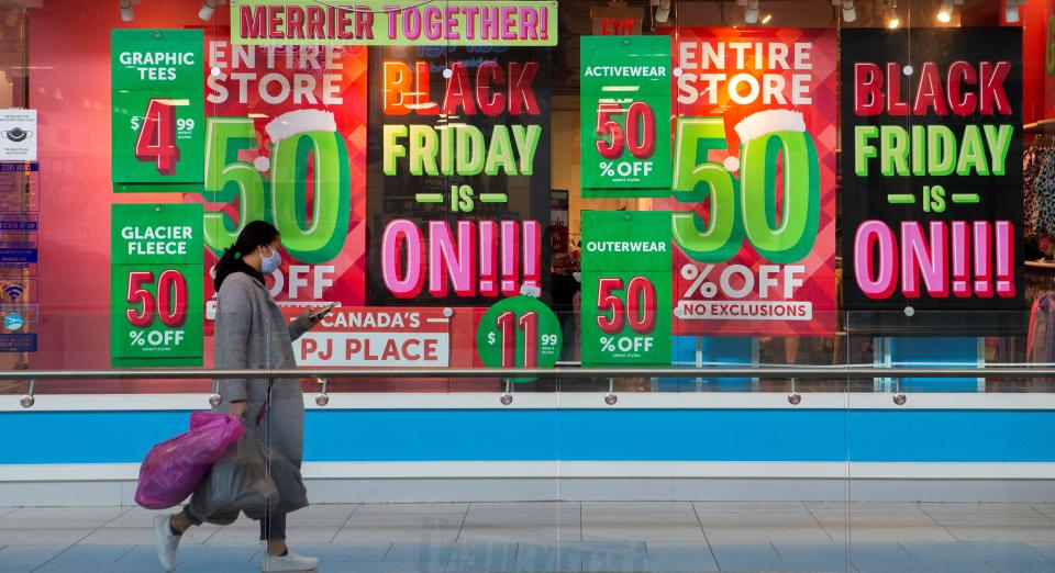 A woman walks past a store's window with posters of Black Friday sales in Mississauga, the Greater Toronto Area, Canada, on Nov. 26, 2021. Many Black Friday shoppers here returned to stores in person this year. (Photo by Zou Zheng/Xinhua via Getty Images)