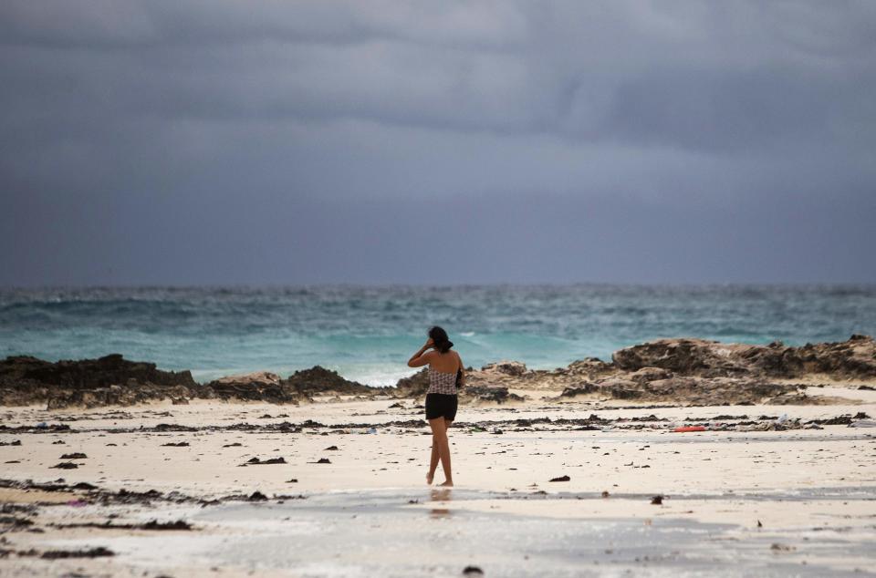 A woman walks on the beach in Cancun