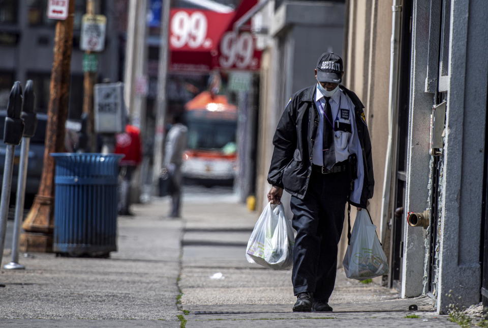 Hempstead, N.Y.: A man wearing a security guard uniform and a mask due to coronavirus concerns walks down a street carrying groceries in Hempstead, New York on April 8, 2020. (Photo by J. Conrad Williams Jr./Newsday via Getty Images)