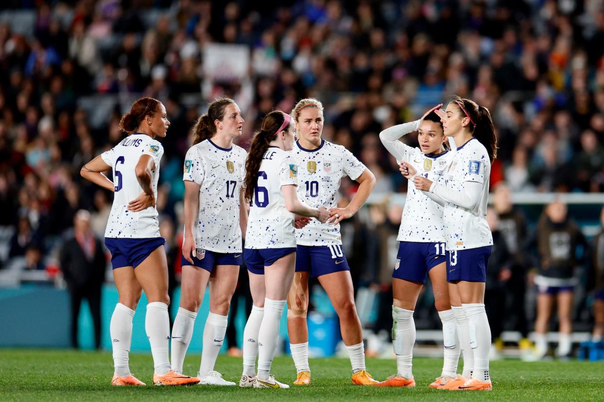 US Women's National Team players group together to talk on the pitch.