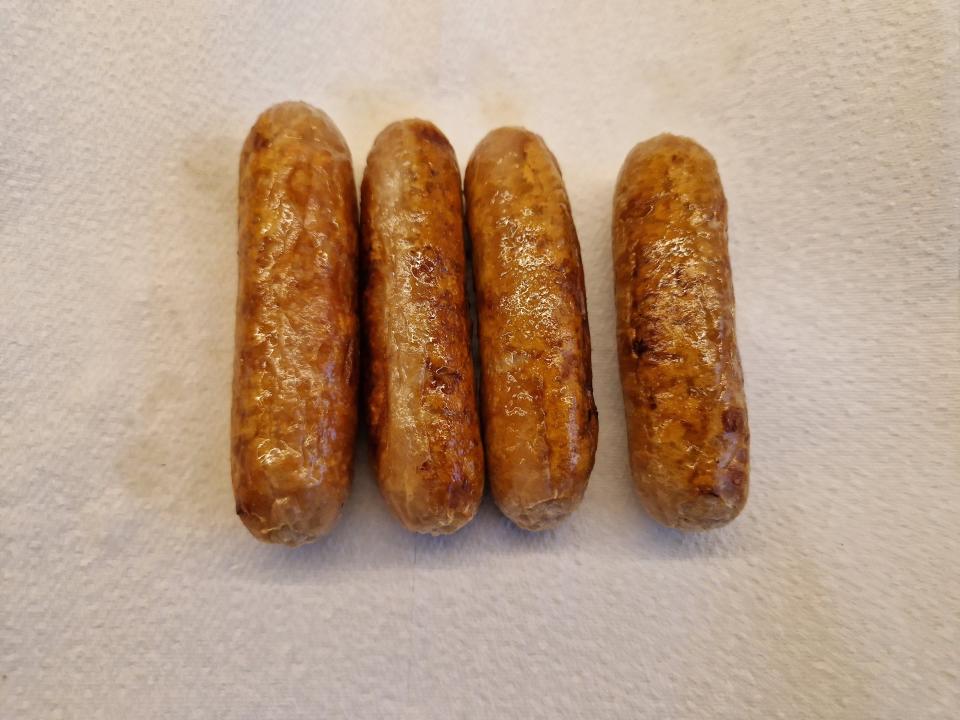 four cooked sausage links on a paper towel