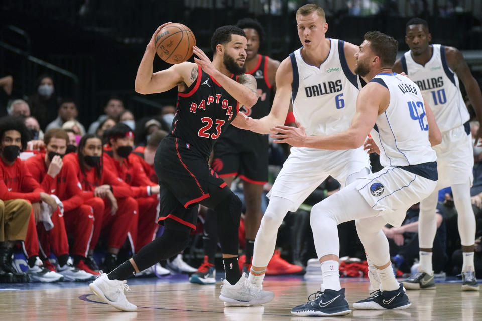 Toronto Raptors guard Fred VanVleet (23) keeps the ball from Dallas Mavericks center Kristaps Porzingis (6) and forward Maxi Kleber (42) during the first quarter of an NBA basketball game in Dallas, Wednesday, Jan. 19, 2022. (AP Photo/LM Otero)