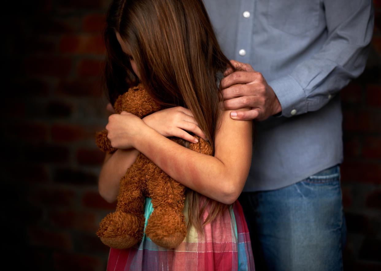 A girl hugging a stuffed toy with a man gripping her shoulders. (PHOTO: Getty Images)