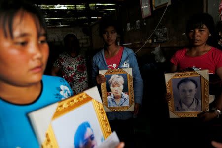 Women pose while holding portraits of their killed relatives (L-R) Aik Sai, Aik Maung and Aik Lort after their bodies were found in a grave last June at Mong Yaw village in Lashio, Myanmar July 10, 2016. REUTERS/Soe Zeya Tun