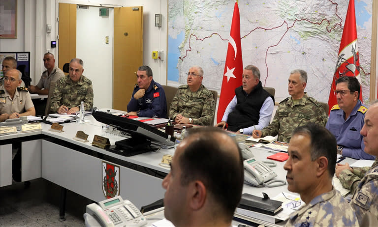 Turkey's Defense Minister Hulusi Akar, center, sits with Turkish army's top commanders in an operation room at the army headquarters, in Ankara, Turkey, Wednesday, Oct. 9, 2019. Turkey's Defense Ministry says Turkish ground forces have moved across the border to fight against Kurdish fighters in northeastern Syria, hours after Turkish jet and artillery pounded areas in Syria's northern border. (Turkish Defence Ministry via AP, Pool)