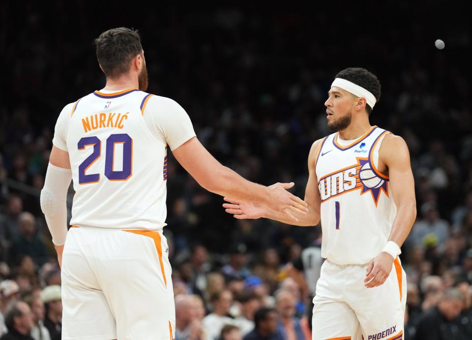 Phoenix Suns center Jusuf Nurkic (20) and Phoenix Suns guard Devin Booker (1) slap hands during the first half of the game against the Minnesota Timberwolves at Footprint Center in Phoenix on April 5, 2024.