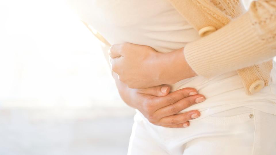 Mujer con las manos sobre su abdomen en gesto de dolor