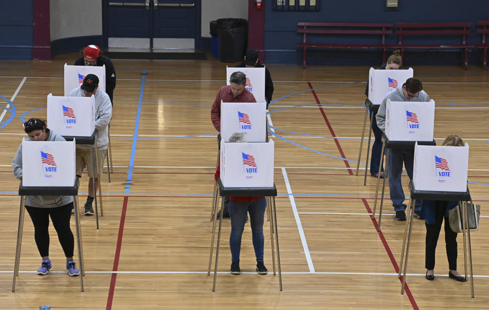 Voters standing at voting booths fill out their ballots.