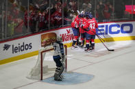 Members of the Washington Capitals celebrate Aliaksei Protas' goal in front of Winnipeg Jets goaltender Connor Hellebuyck in the third period of an NHL hockey game, Tuesday, Jan. 18, 2022, in Washington. Washington won 4-3 in overtime. (AP Photo/Patrick Semansky)