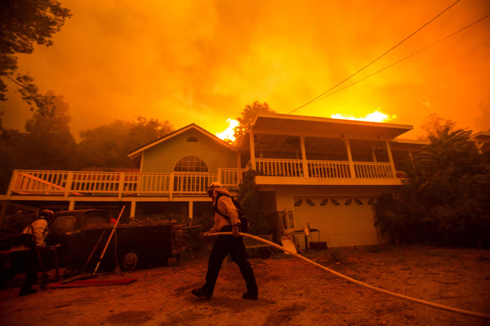 Firefighters work near a home as the Lake Hughes fire burns in the background, in Angeles National Forest on Wednesday, Aug. 12, 2020, north of Santa Clarita, Calif. (AP Photo/Ringo H.W. Chiu)