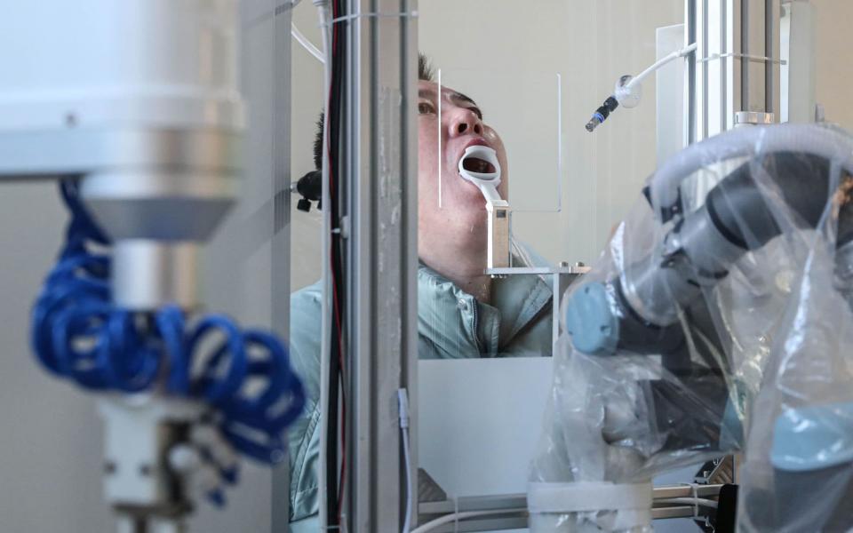 A robot machine takes a swab sample from a man to test for the Covid-19 coronavirus in Shenyang, in northeastern China's Liaoning province - AFP