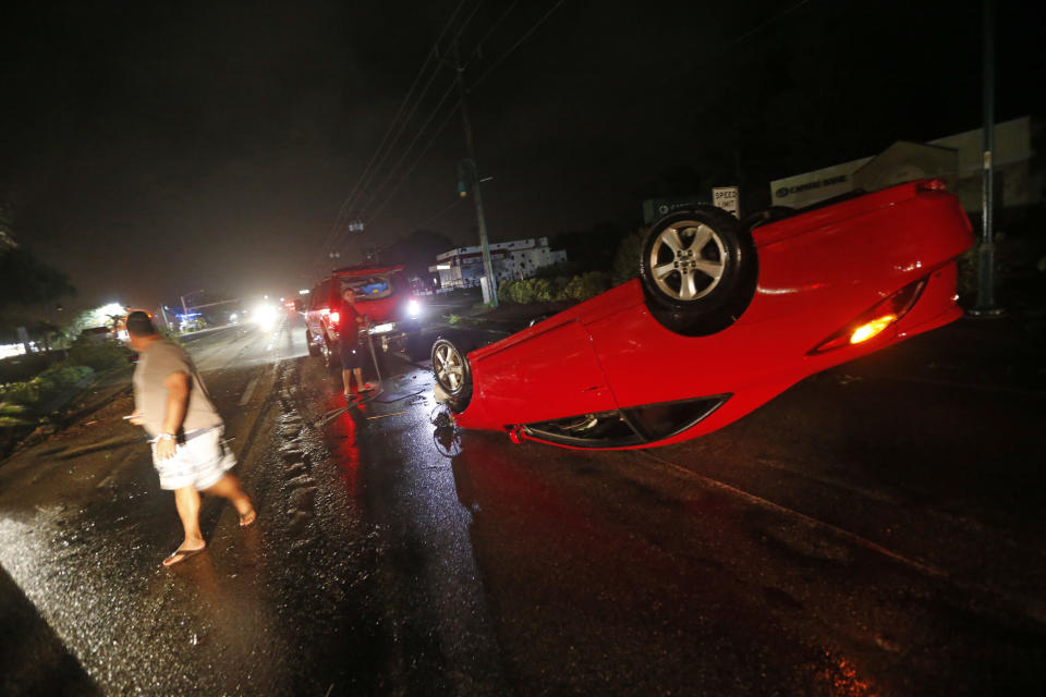 <p>In Cape Coral, Florida, stehen Einwohner neben einem vom Hurrikan umgeworfenen Fahrzeug. (Bild: Gerald Herbert/AP/dpa) </p>