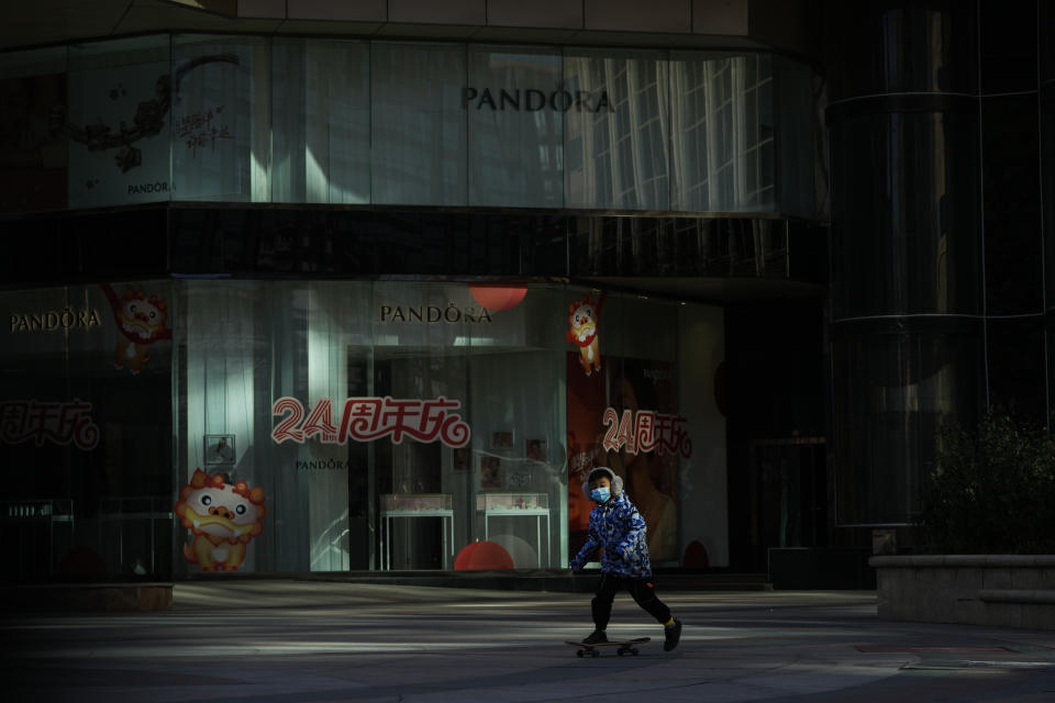 A child rides a skateboard through a deserted walkway outside a closed shopping mall in Beijing, Sunday, Dec. 4, 2022. China on Sunday reported two additional deaths from COVID-19 as some cities move cautiously to ease anti-pandemic restrictions amid increasingly vocal public frustration over the measures. (AP Photo/Andy Wong)