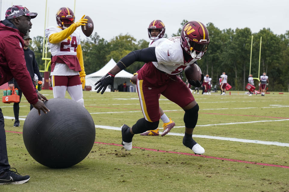 Washington Commanders running back Brian Robinson Jr., right, works out during practice at the team's NFL football training facility, Wednesday, Oct. 5, 2022, in Ashburn, Va. Robinson was shot twice in the right leg Aug. 28 in Washington, was taken to a hospital, underwent surgery and was released a day later. The bullets missed all the major ligaments and bones in his knee. (AP Photo/Alex Brandon)