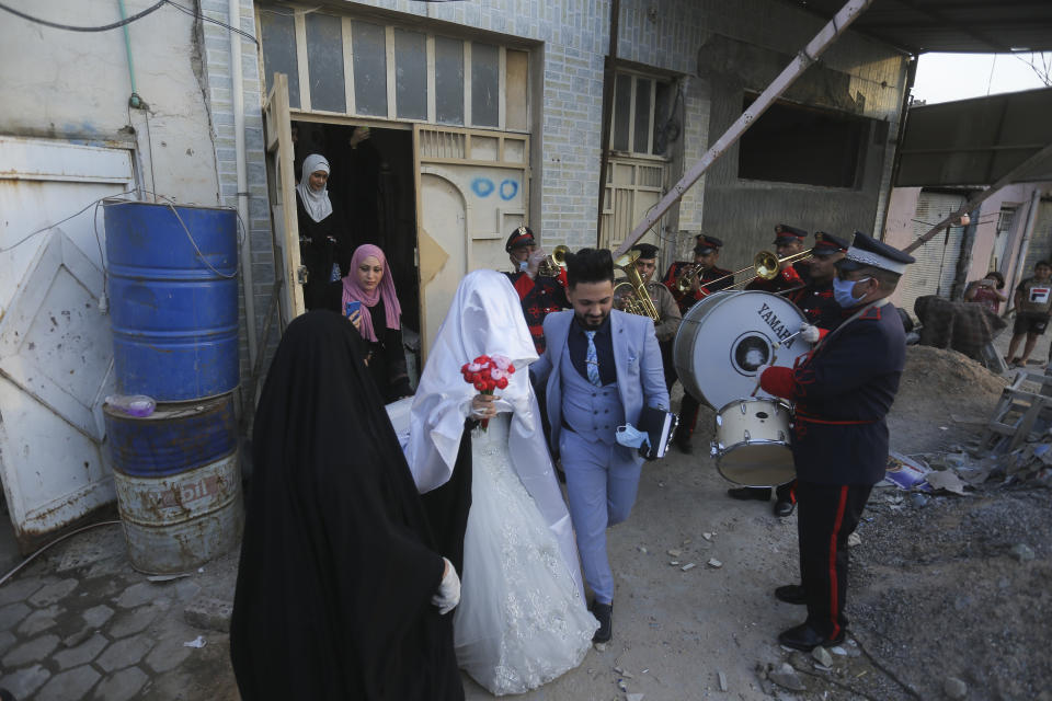 In this Thursday, April 9, 2020 photo, police brass band plays for Ahmed Khaled al-Kaabi and his bride Ruqaya Rahim during their wedding in Najaf, Iraq, hardest hit town by coronavirus in the country with government banned large public gatherings. Unwilling to postpone the wedding, al-Kaabi asked the local security forces to help him wed his beloved. The police responded by providing the groom vehicles blasting music to bring his bride to the family home for a small celebration of just six people. (AP Photo/Anmar Khalil)