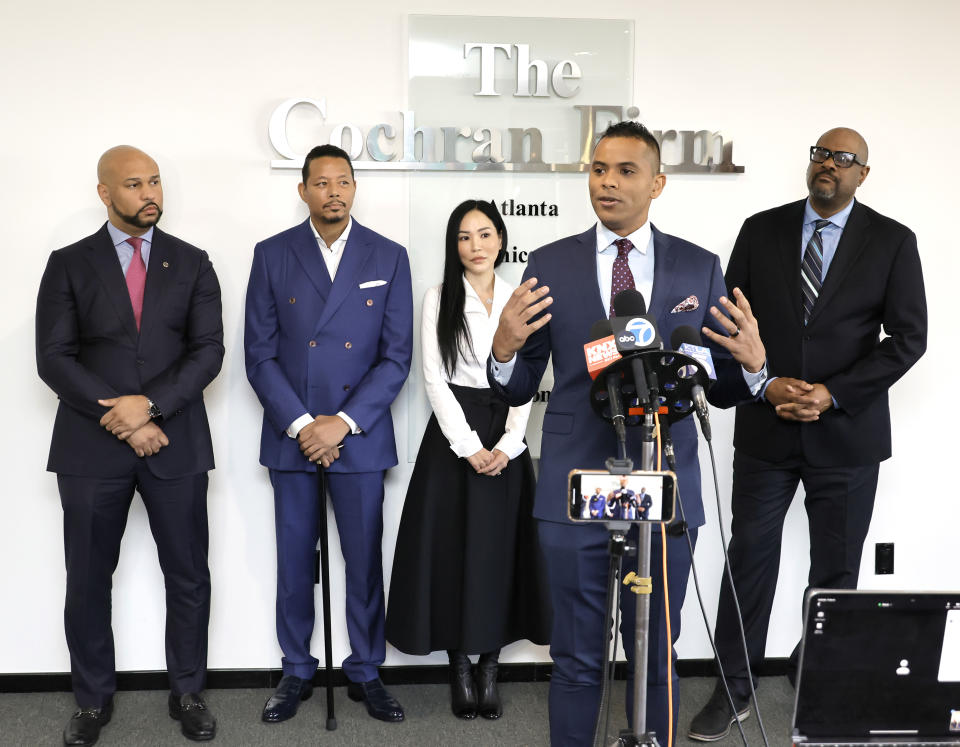 Terrence Howard, speaking at podium, with (L-R,rear) attorney Carlos Moore, attorney James Bryant, Howard’s wife Miranda Pak, and attorney Brian Dunn announces lawsuit against CAA over “Empire” salary at The Cochran Firm on December 08, 2023 in Los Angeles, California.