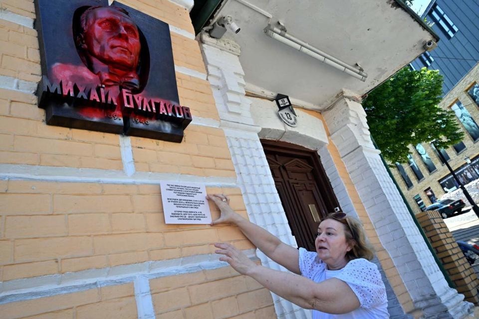 A woman stretches her arms up a wall.