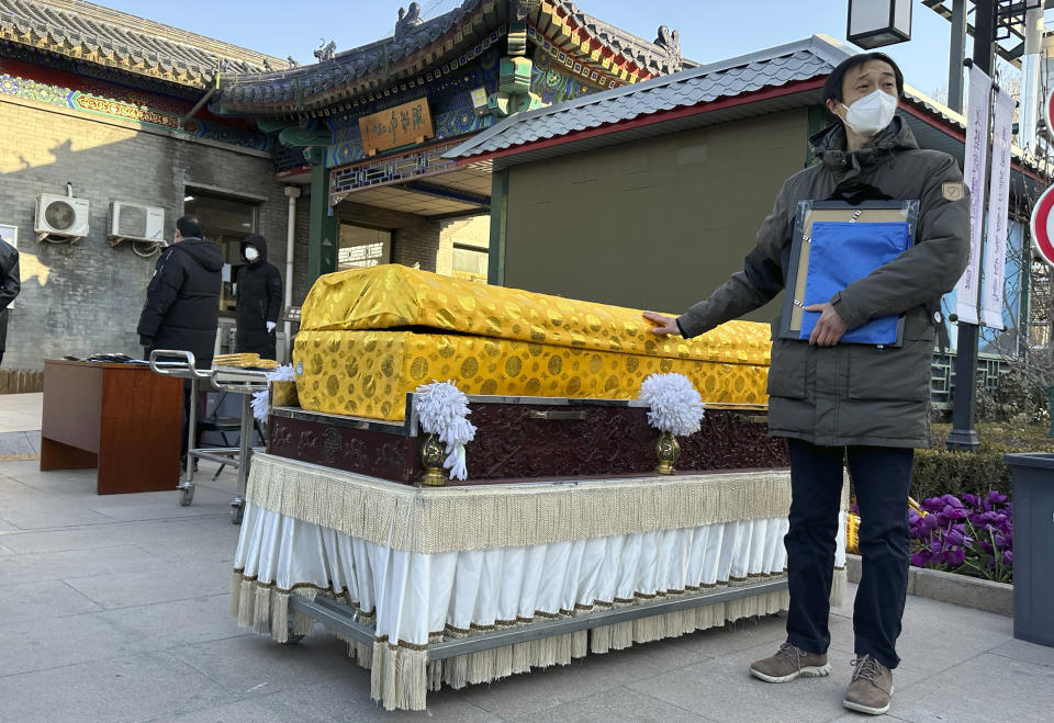 CORRECTS TO DELETE THE ERRONEOUS FACT OF THE NUMBER OF THE DEATHS IN 2023 - FILE - Family members in protective gear collect the cremated remains of their loved one bundled with yellow cloth at a crematorium in Beijing on Dec. 17, 2022. China's population dropped by 2 million people in 2023 in the second straight annual drop as births fell and deaths jumped after the lifting of COVID-19 restrictions, the government said Wednesday, Jan. 17, 2024. (AP Photo/Ng Han Guan, File)