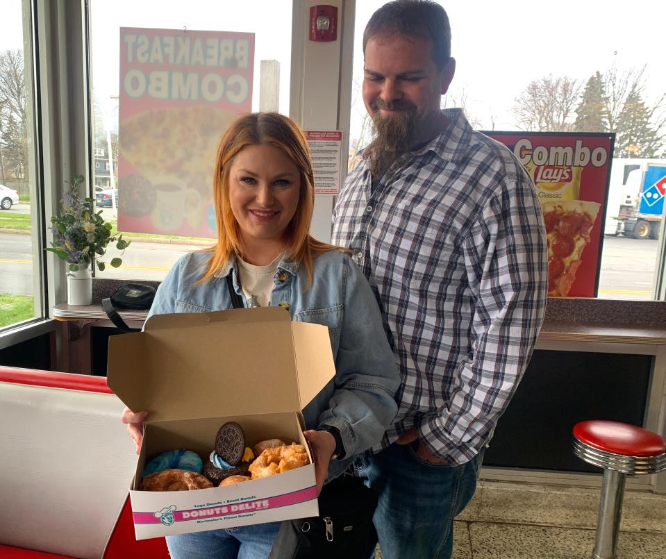 Brittnay Henderson, of Rochester, and Jeremy Klace of the Buffalo area show off their Donuts Delite haul, including Galaxy and Solar Eclipse doughnuts, on April 8, 2024.