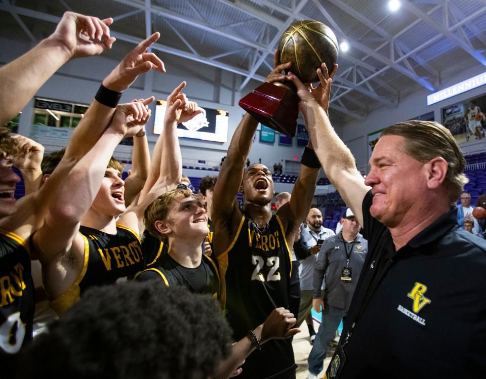 Bishop Verot Vikings players and staff celebrate with the trophy after defeating the Fort Myers Green Wave in the Hugh Thimlar tribute game during the 50th annual City of Palms Classic at Suncoast Credit Union Arena in Fort Myers on Wednesday, Dec. 20, 2023.