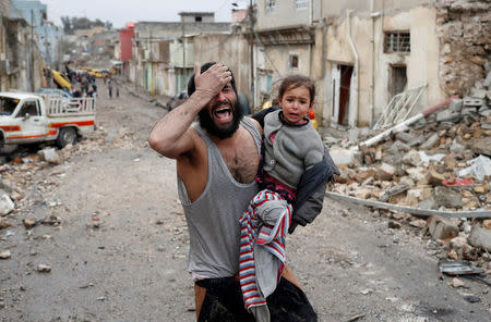 A man cries while he carries his daughter as he walks from Islamic State controlled part of Mosul towards Iraqi special forces soldiers during a battle in Mosul, Iraq, March 4, 2017. REUTERS/Goran Tomasevic