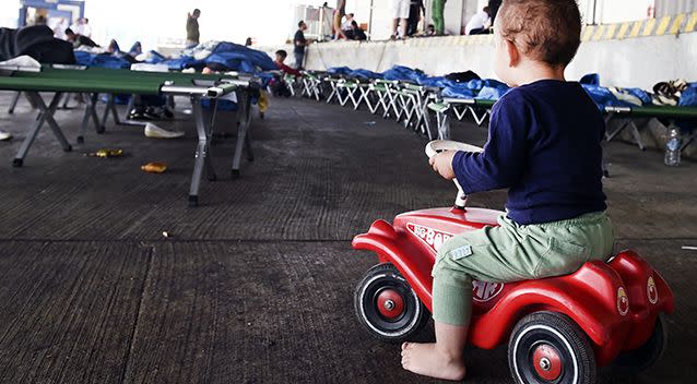 A child can be seen riding a toy car inside a migrant care centre. Source: AAP