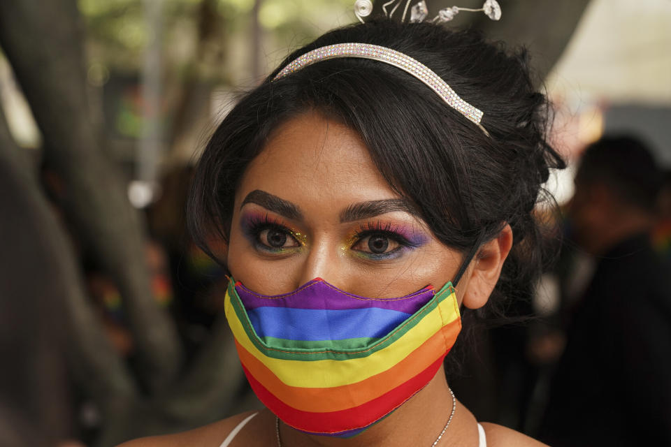Una mujer con una mascarilla que tiene los colores del arcoíris escucha a un juez de lo civil durante una ceremonia masiva de bodas igualitarias organizada por las autoridades de la Ciudad de México como parte de las celebraciones del mes del orgullo LGBT, el viernes 24 de junio de 2022. (AP Foto/Fernando Llano)