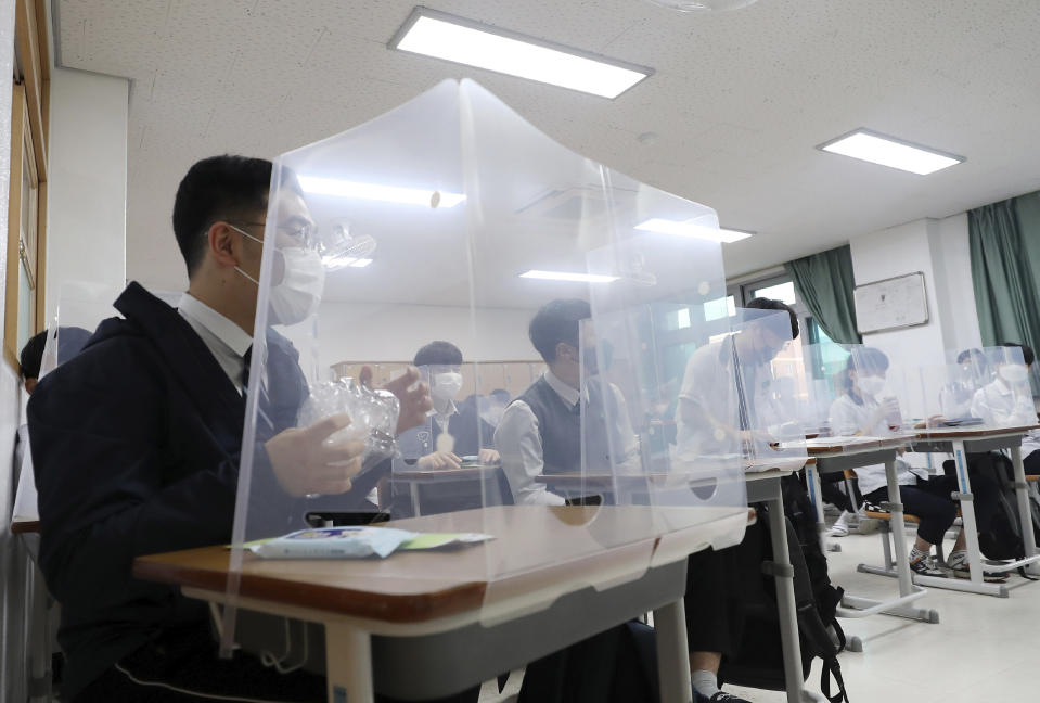 Senior students wait for a class to begin with plastic shields placed on their desks at Jeonmin High School in Daejeon, South Korea, Wednesday, May 20, 2020. South Korean students began returning to schools Wednesday as their country prepares for a new normal amid the coronavirus pandemic. (Kim Jun-beom/Yonhap via AP)