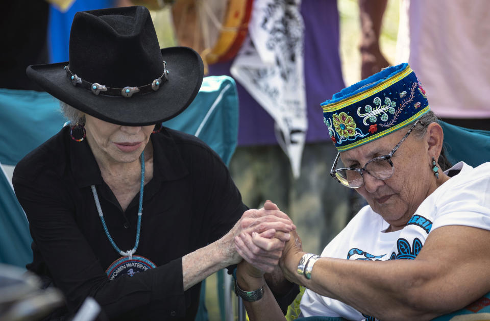 Actress and activist Jane Fonda, left, locks hands with Grandmother Mary Lyons after they prepared to perform a traditional water ceremony, on Monday, June 7, 2021, in Clearwater County, Minn. More than 2,000 Indigenous leaders and "water protectors" gathered in Clearwater County from around the country to protest the construction of Enbridge Line 3. The day started with a prayer circle and moved on to a march to the Mississippi headwaters where the oil pipeline is proposed to be built. (Alex Kormann/Star Tribune via AP)