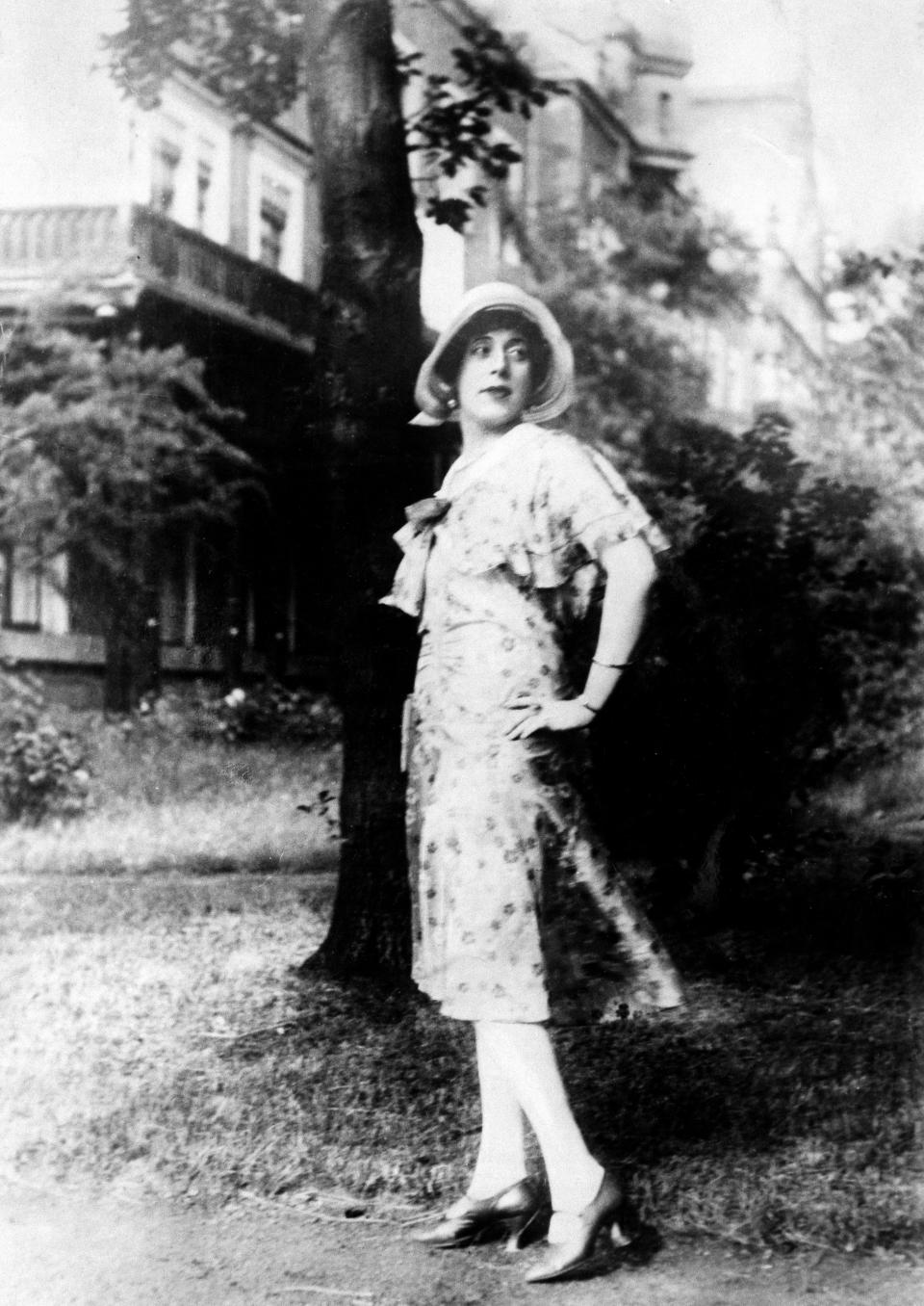 Black-and-white image of Lili Elbe posing next to a tree.