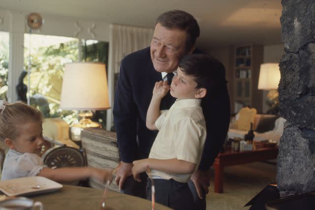 <p>John Dominis/The LIFE Picture Collection/Shutterstock</p> John Wayne at home with his son Ethan and daughter.