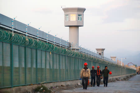 Workers walk by the perimeter fence of what is officially known as a vocational skills education centre, under construction in Dabancheng in Xinjiang Uighur Autonomous Region, China September 4, 2018. REUTERS/Thomas Peter/Files